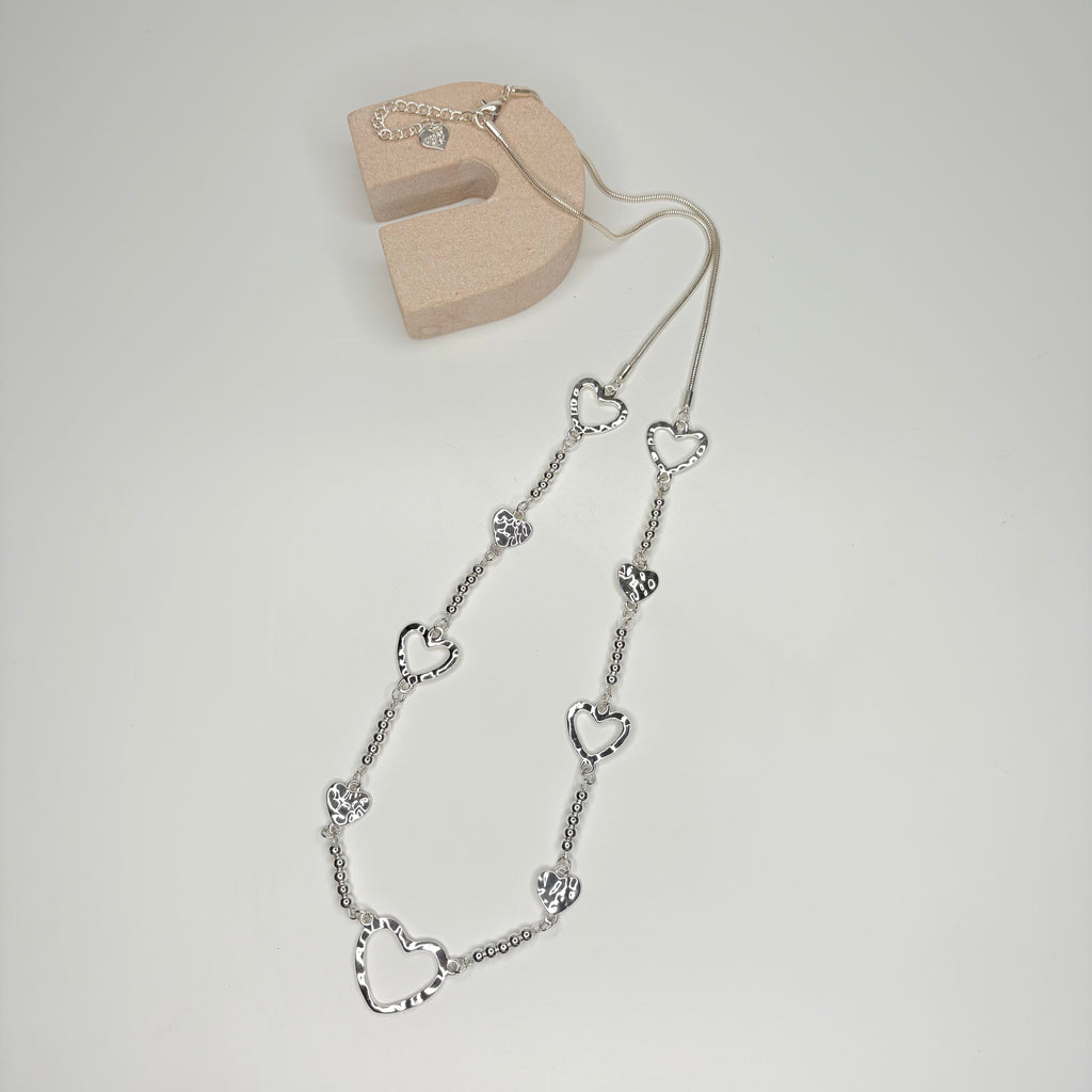Long silver necklace, with battered metal heart stations