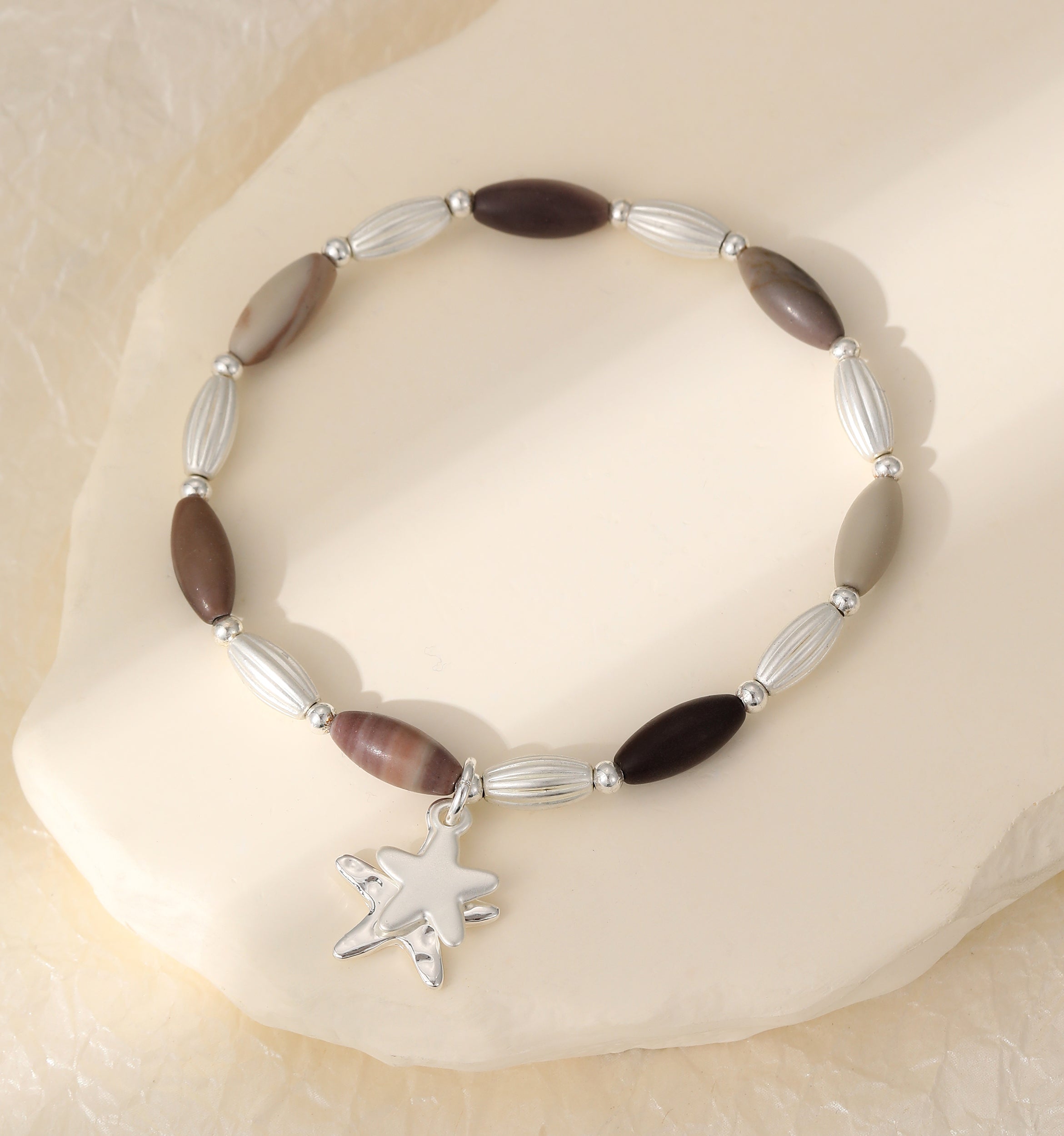 Elasticated bracelet in silver & earthy tones, with star pendant