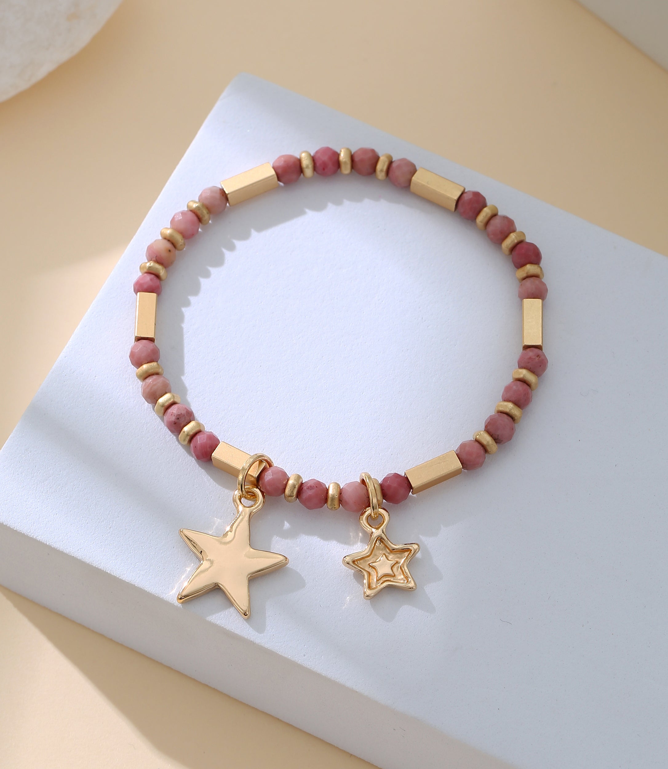 Elasticated bracelet in gold, with pink beads and star pendant