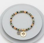 Elasticated bracelet in gold, green & earthy tones, with tree pendant