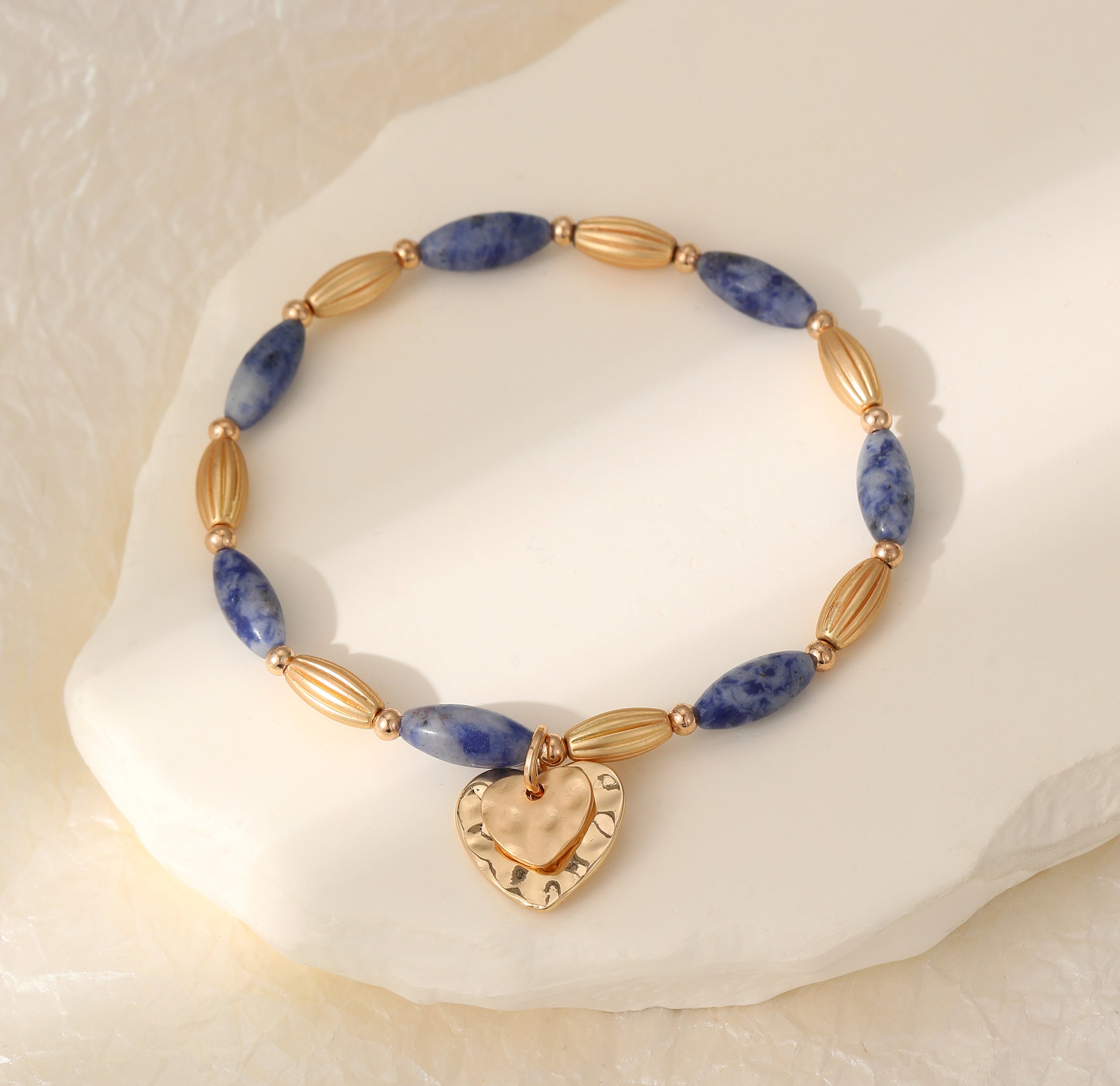 Elasticated bracelet in gold & blue tones, with heart pendant