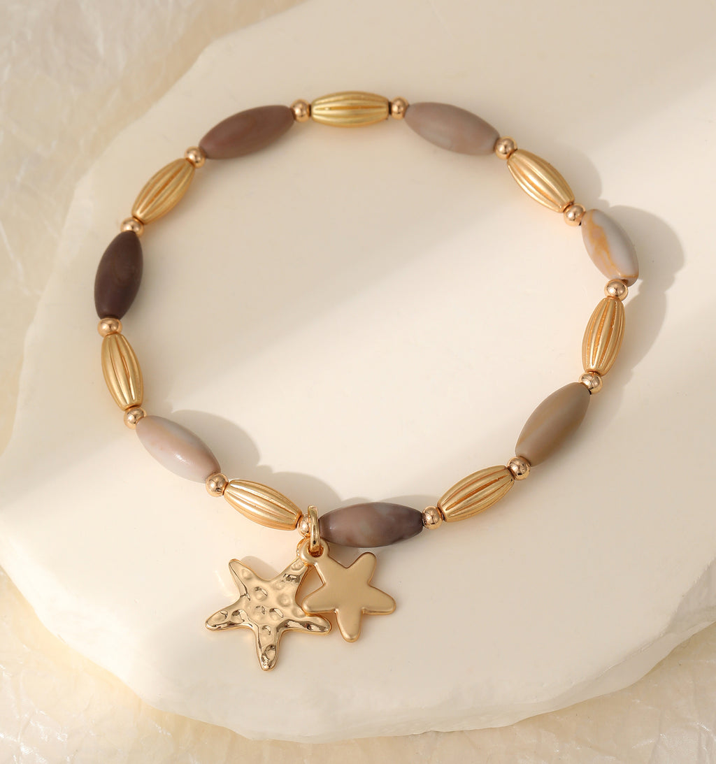 Elasticated bracelet in gold & earthy tones, with star pendant