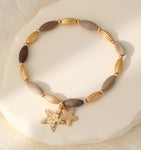Elasticated bracelet in gold & earthy tones, with star pendant