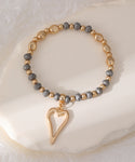 Elasticated bracelet in matte gold with heart pendant